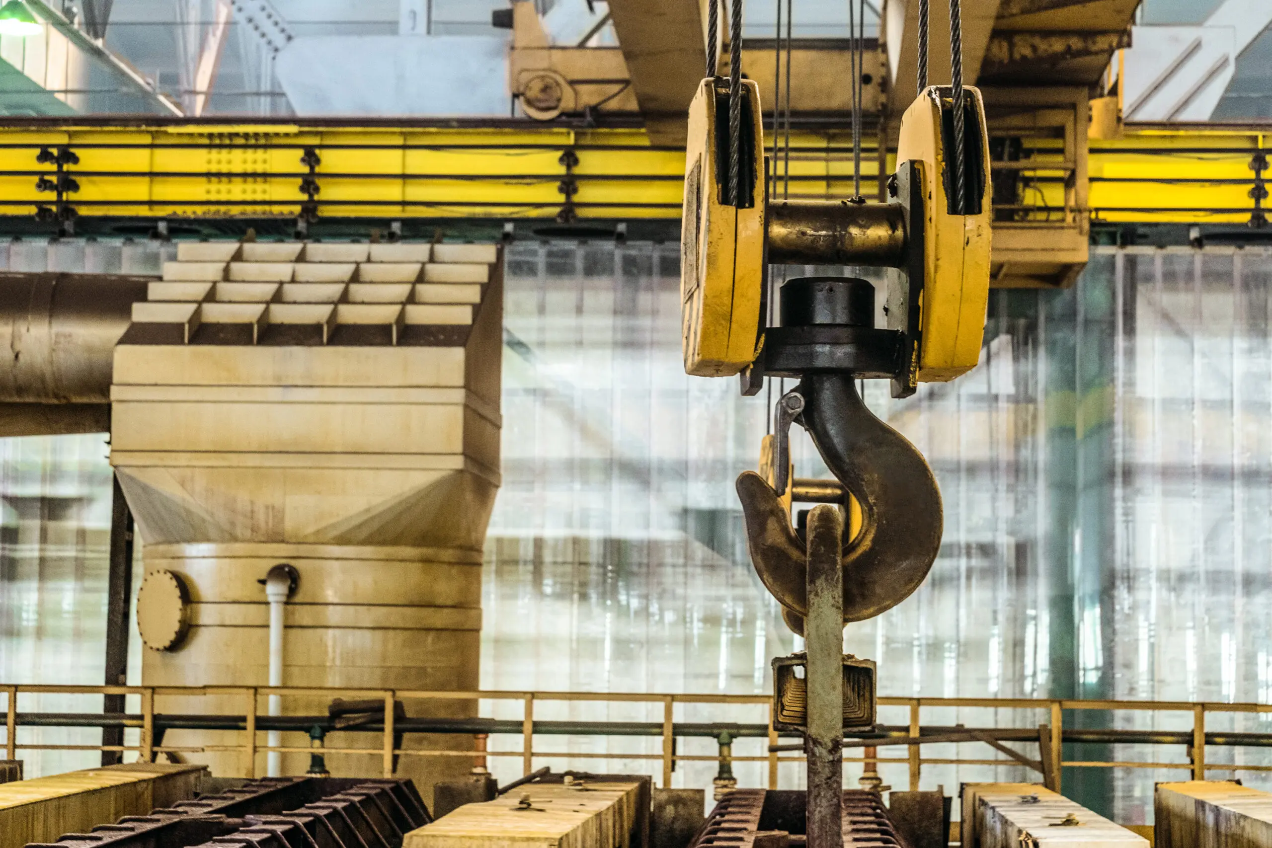 Steel hook of overhead crane over industrial equipment Industrial crane hook lifting metal beams in a factory.