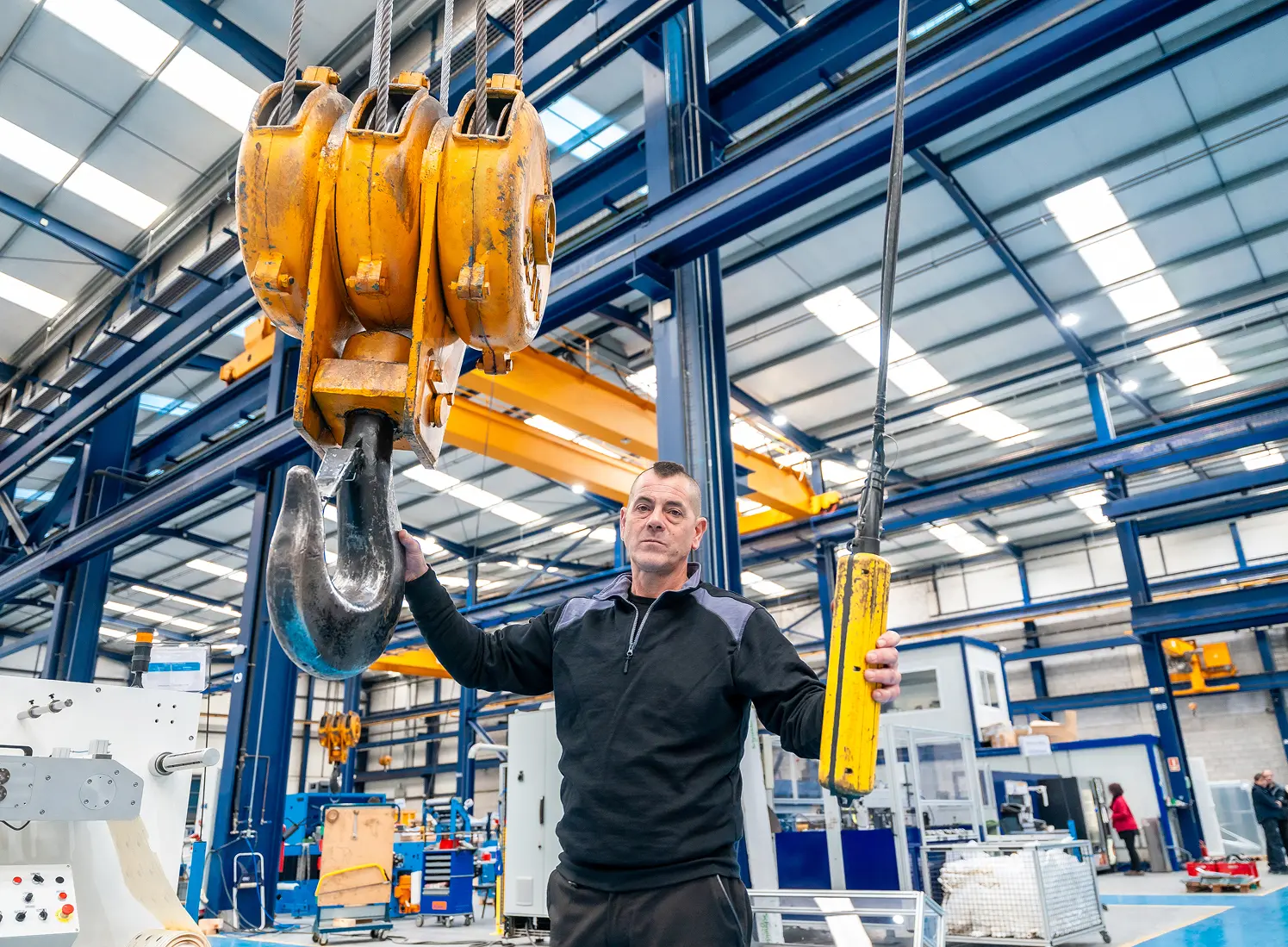 Man operating industrial crane in factory.