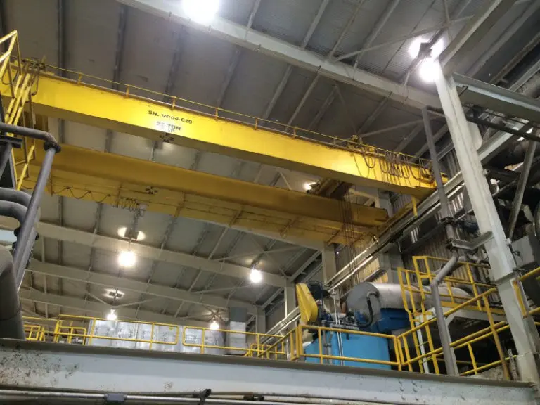 Yellow industrial overhead crane in factory setting.